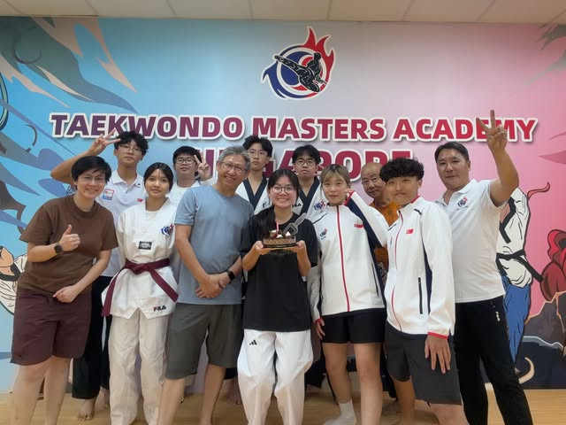 Group photo with coaches at the academy wall